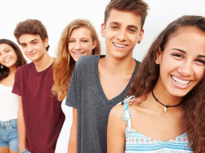 The image shows a group of young people, likely friends or family members, posing for a photo with smiles on their faces.