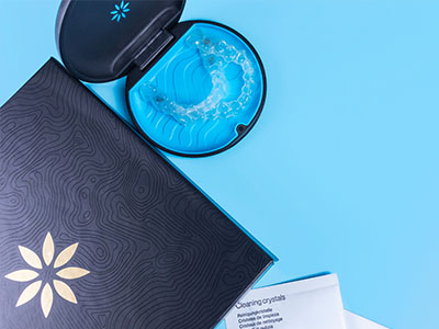 A blue toothbrush with a black and gold handle, placed on top of a closed box or package with a floral design.